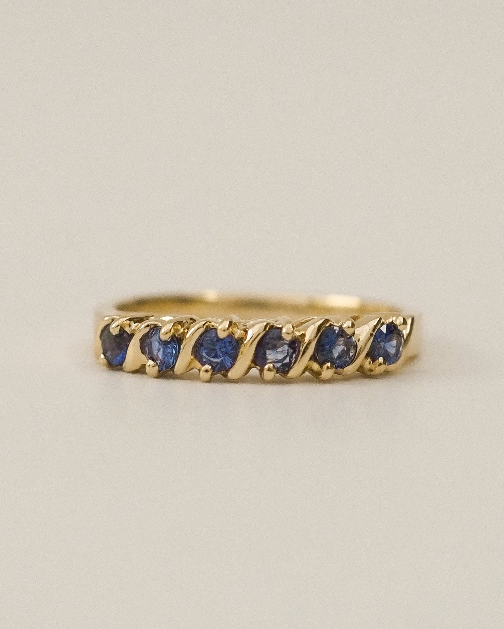 Gold ring with blue gemstones on a beige background