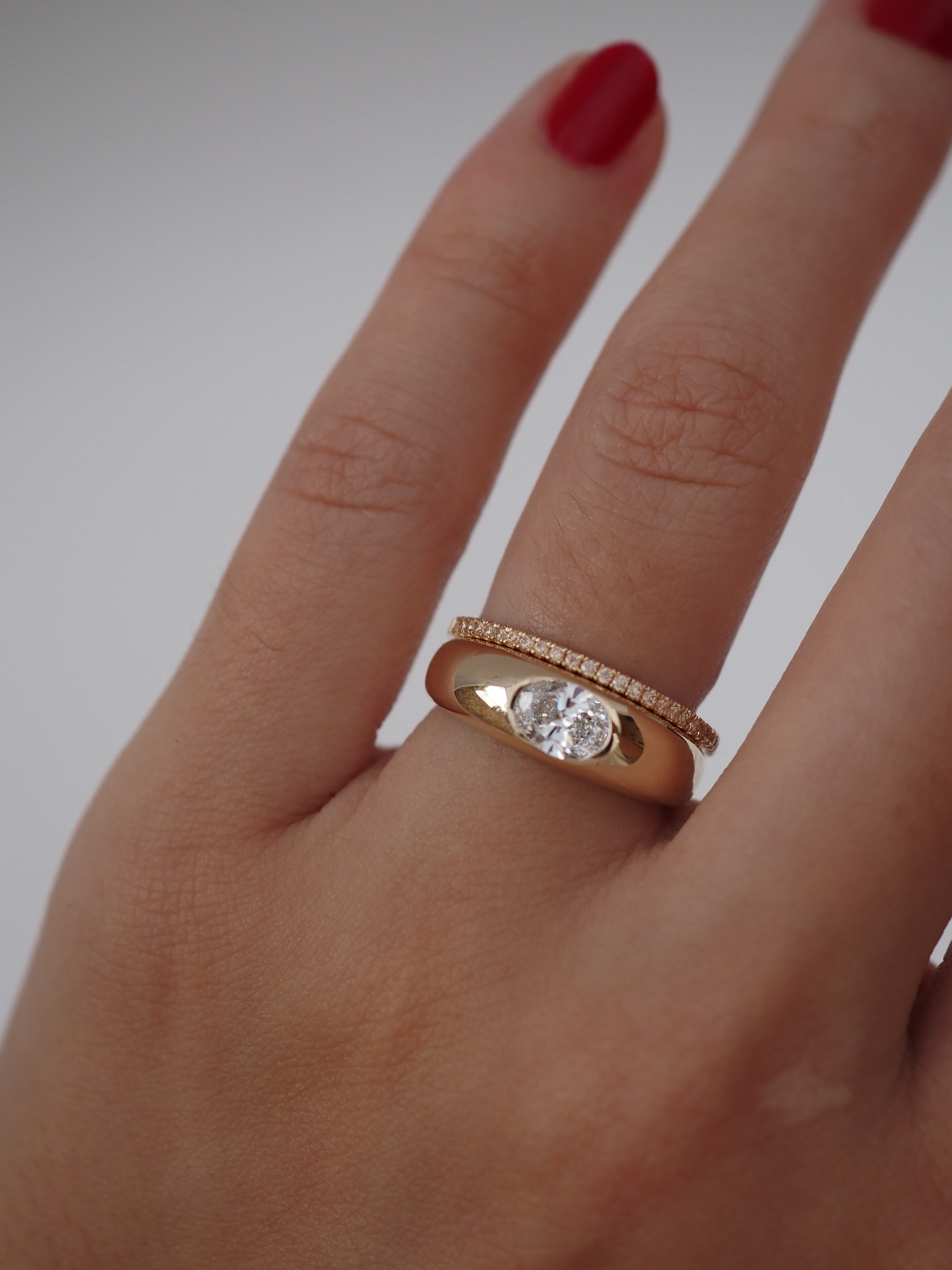 Gold ring with a diamond on a finger against a white background